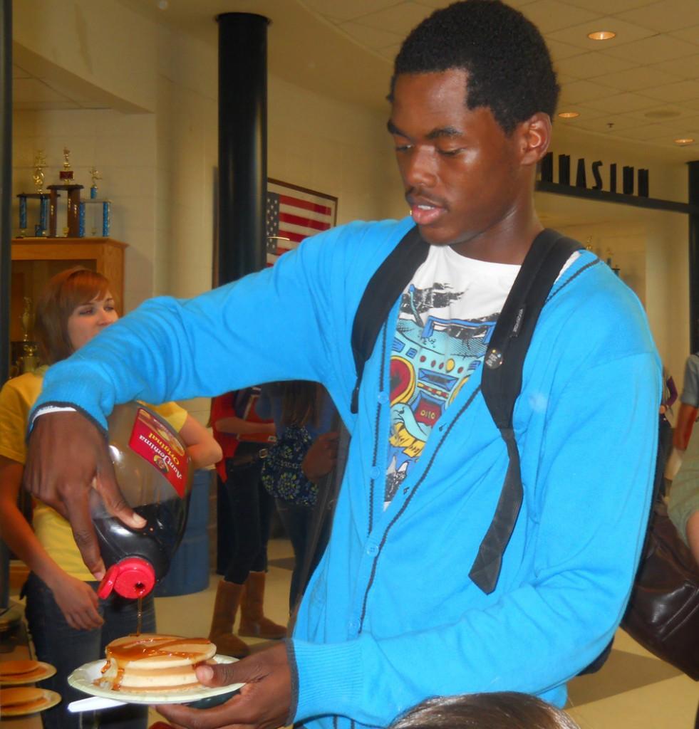   Before heading to his first period class,  senior Joshua Roberts tops off his plate of pancakes with some Aunt Jemima syrup.