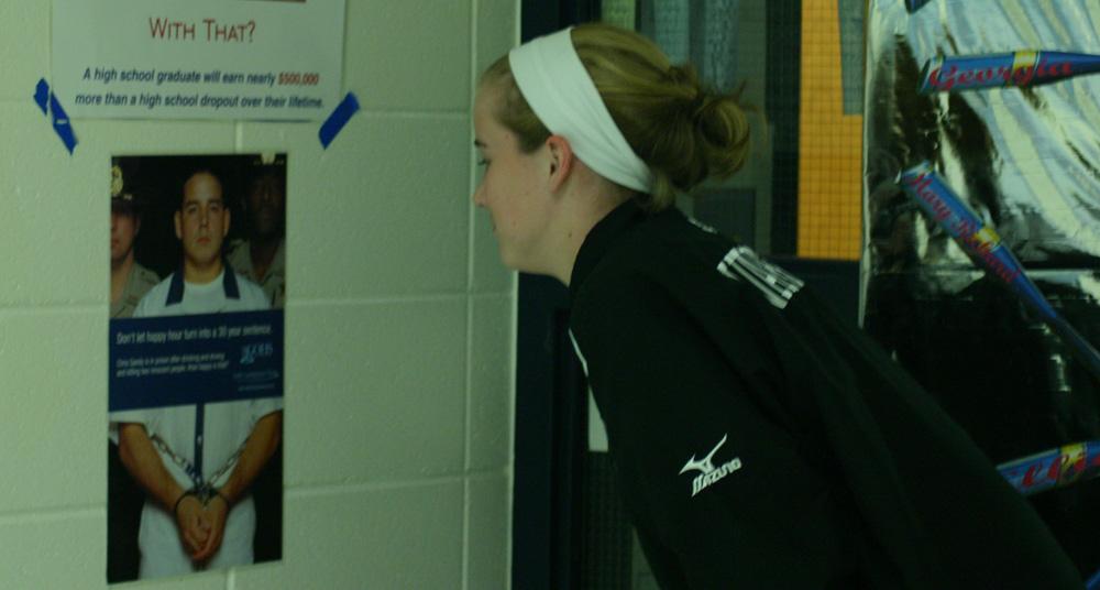 Jenny Tomasello looks at the poster that hangs on the wall outside Coach Mark Williamsons door. It previously hung outside the attendance office for many years.Tomasello now fully understands the meaning behind the poster after hearing Sandys story.