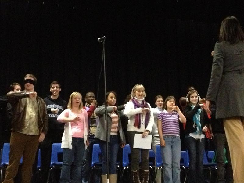 Rising Starr Chorus teacher Christie Todd leads the students of the Special Education Music Therapy class in a vocal warm-up. The students sing a musical scale and use hand motions for each of the eight notes. 