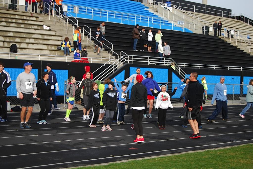 Two trainers from Snap Fitness help get some blood flowing for some runners before the race by doing some jumping-jacks and lunges. 