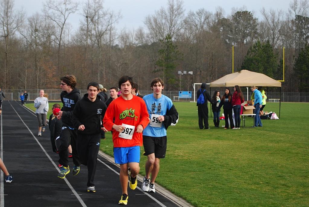 Freshman Taylor Nelson leads a group of other runners warming up on the track before the race. 