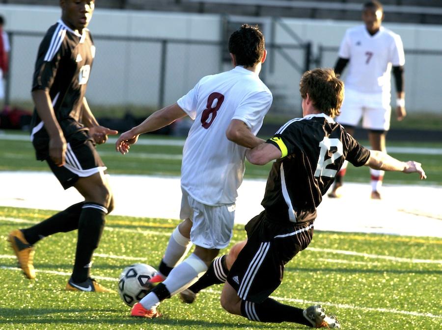 Senior Kyle Ulversoy (12) slide tackles a Walton player to knock away the ball and stop the Raiders attack toward the goal.