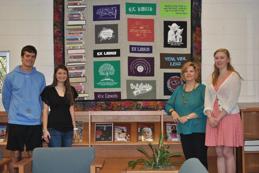 Ex Libris co-sponsor Leigh Anne Hanie gathers with club officers (from left) Logan Siddall, Lydia Powell, and Kristin Higginbotham around the newly hung T-shirt quilt in the Media Center.