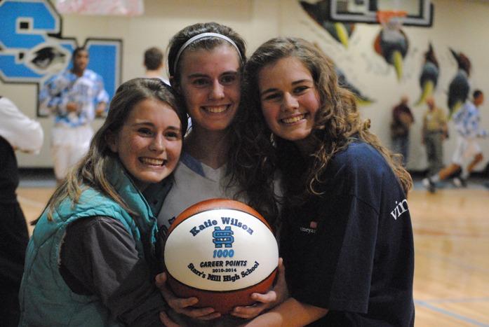 Senior Katie Wilson (center) takes a picture with her 1,000 point commemorative basketball. With her are her two sisters, Meghan (left) and Natalie after the game against Whitewater.