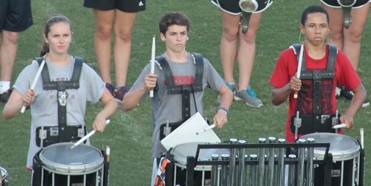 Percussion members Kacey Yonkovitz, Brian Buck and Jawel Zimbabwe work on their synchronized precision,  which is a required WHAT?  Be more specific in what this means.