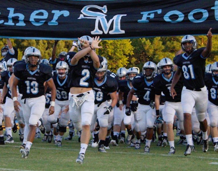 Chase Reinert (13), Charlie Gable (2) and Terence Harper (81) lead the team onto the field for the first game of the season against Whitewater High. 