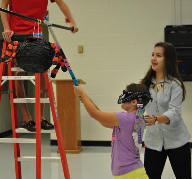 Junior Maggie Zarate guides third grader Sophia as she prepares to take a swing at the piñata. 