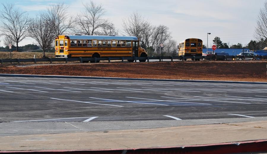 Buses roll out of the South Complex after the last bell, passing the completed golf cart parking lot. 