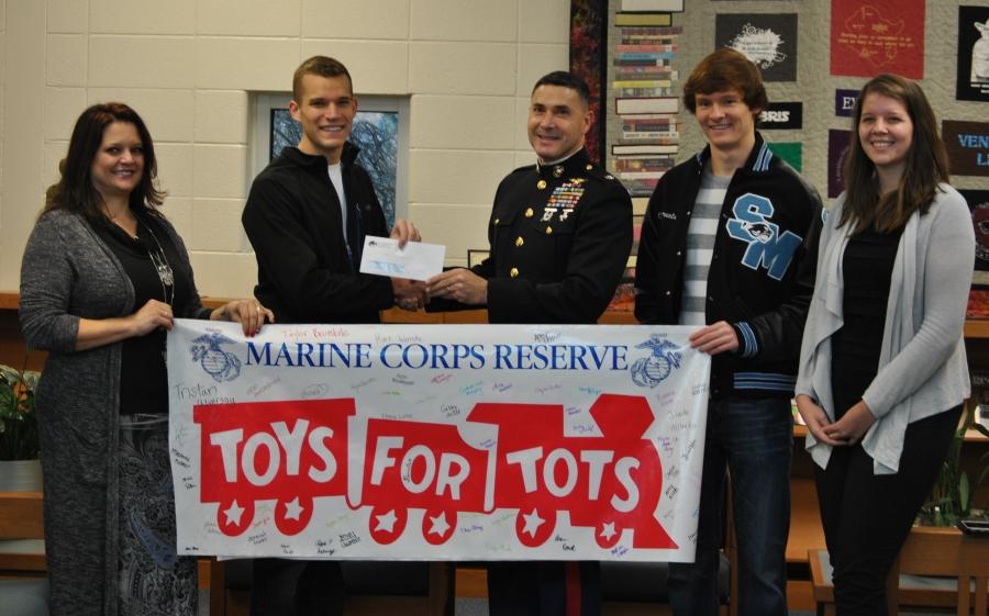 National Honor Society President Kurt Wenske presents a check for $1,500 to Lt. Col. James Ruvalcaba of the U.S. Marines for their  annual Toys for Tots campaign.  NHS members sold paper trains for a minimum donation of $1 each.  Sponsors Tara Burnette (left) and Katie Tucker hold the banner.  Cody Clements (right) is the clubs historian.  