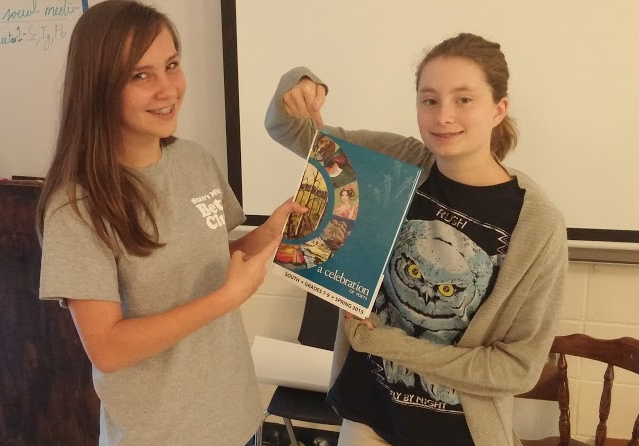 Sophomores Dana Gould and Ashton Long pose with the most recent publication of The Celebration of Poets that sports a poem from each of the girls.