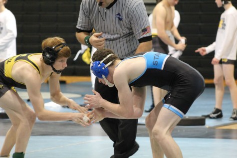 Wrestlers face off during area duals, awaiting the referee to signal the beginning of the match.