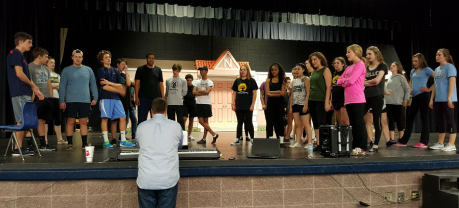 Before rehearsing a dance, the full cast runs through the vocals of the number with and without music to prepare. Musical director Zachary Stutts reminds the students, “If you have fun, it’ll sound fun, and you’ll enjoy it that much more.”