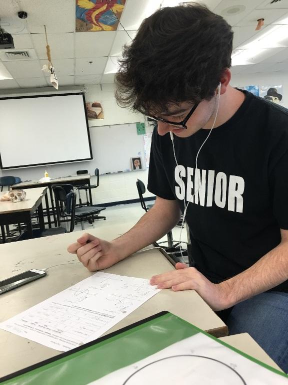 A student focuses on his work while listening to some of his favorite tunes. Students choose to listen to music while doing schoolwork to lift their mood and help them concentrate.