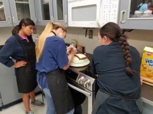 Students ice a cake during a lab in food and wellness teacher Cheryl Clower’s class.  Clower will retire after 25 years of teaching and mentoring students. “My favorite part of teaching was the relationships built with my students and seeing my students grow as individuals and leaders for our future,” Clower said.