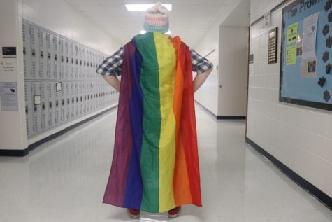 Gay Straight Alliance club member stands in the hallway wearing a transgender flag beanie and the gay pride flag as a cape. The GSA club strives to encourage sexuality and gender diversity in the school. 