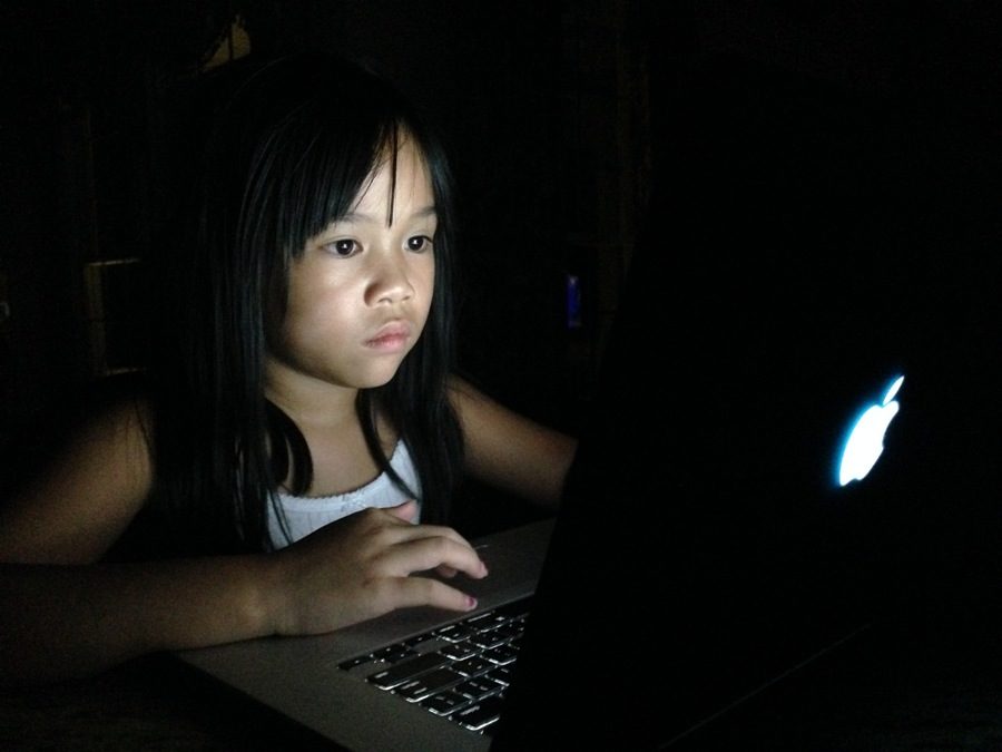 A child intently plays an online game on her laptop. Online games have the potential to appear to be a higher priority than they should be, and they should be considered a case of digital addiction.
