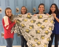 Junior Ally Marshall and seniors Erin Rathje, Marleena Tamminen, and Elena Wernecke hold up the blanket they created for the service project. The blanket, along with a photo of Spanish Honor Society members, will be donated to the children’s hospital.
