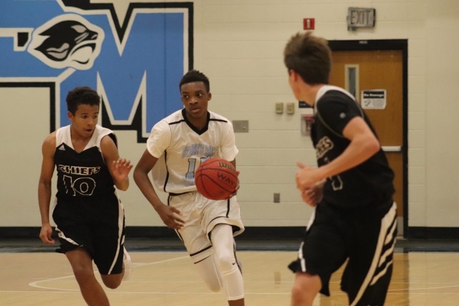 A player on the freshmen basketball team dribbles up the court while keeping two McIntosh players away from the ball. The team started out strong but eventually lost the game due to weak defense and a loss in momentum. 