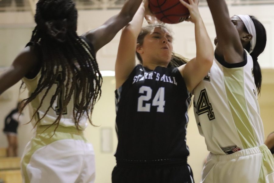 Two Tiger players defend a Panther player attempting a layup. The Fayette County defense shut down the paint and forced the Panthers to settle for outside shots.