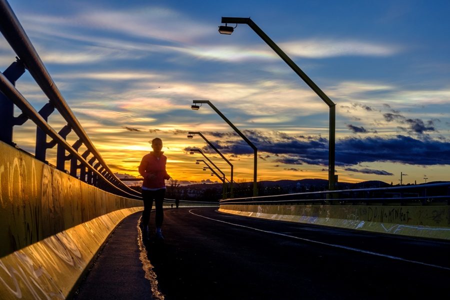 A person jogging begins a workout as the sun sets. While exercising in humid weather is not impossible, it is crucial to take several precautions, such as drinking a sufficient amount of water and putting on lightweight, breathable athletic wear.