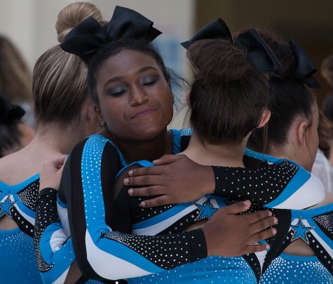 Senior cheerleader Tori Davis hugs a teammate before the team’s routine. The varsity team placed first at the competition at Whitewater, while the JV team finished in third.