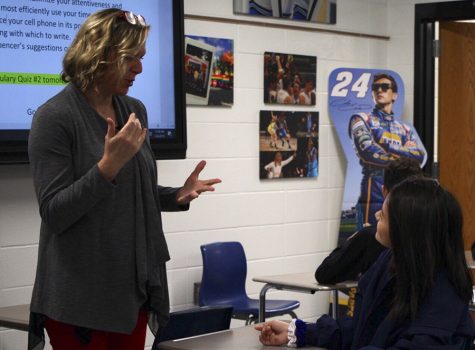 Christine Chatham and Grace Forsberg sign to one another before English class begins. Forsberg had not spoken her first full sentence until the age of eight, but now she can communicate through both sign language and English. 