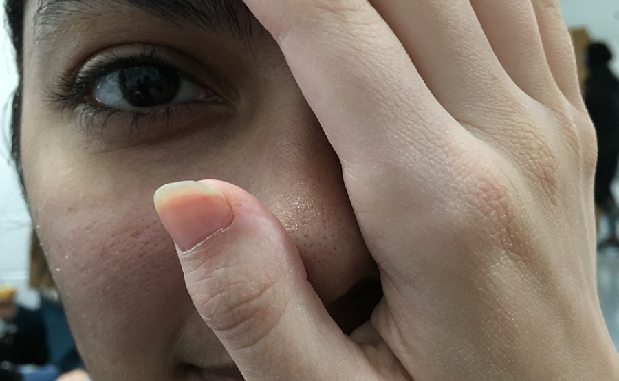 Junior Dhara Padhiar covers her face with white hands, depicting the double standard society has put on her. Society tends to cause problems for kids who identify with two cultures because of the inability to see them in more than one way. 
