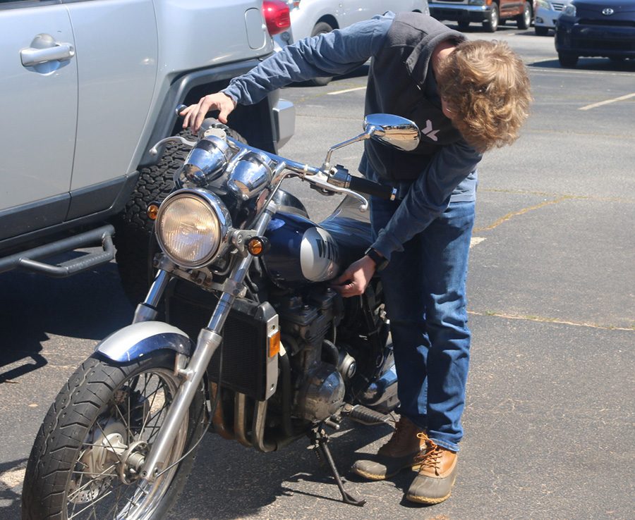 Junior Quinn Biddle starts up his motorcycle in front of his technology class. Biddle got a chance to drive his motorcycle to school so that he may show his accomplishment to the class. 
