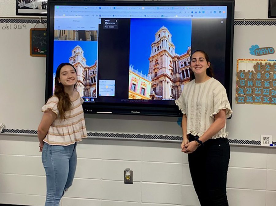 Foreign exchange students Marta Merida and Angela Valdo Perez stand with their presentation after the Interact Club meeting. The students made a presentation about their home country, Spain, and how the country compares to the United States. 