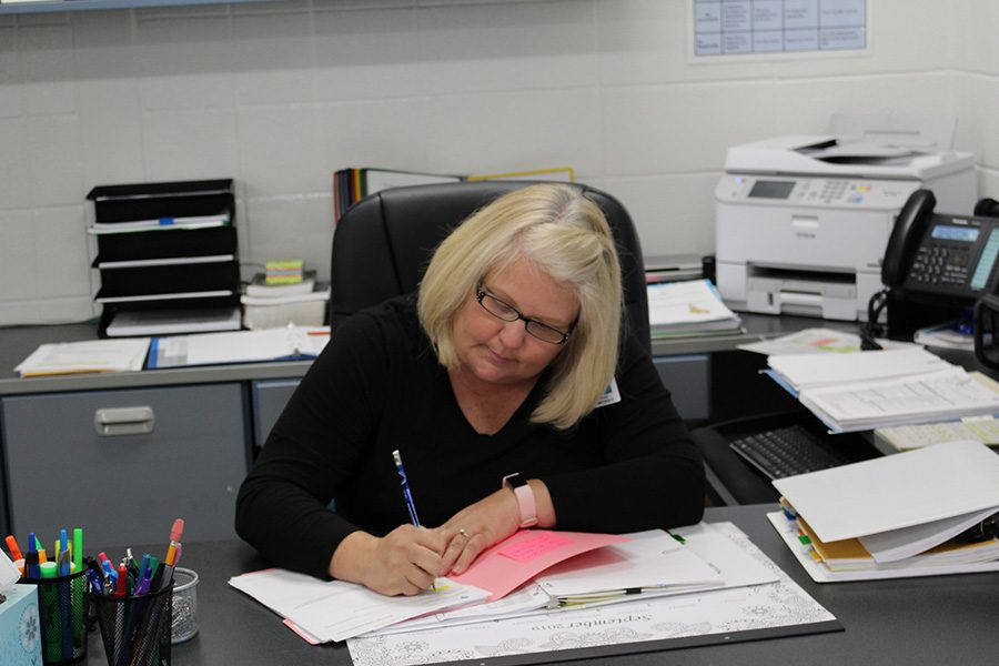 Athletic secretary Stacy Nichols completes paperwork at her desk. Nichols has worked as a secretary since 1994, and now moves from Oak Grove Elementary to the Mill.