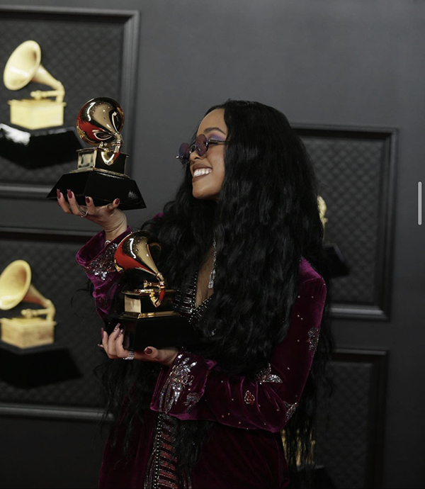 H.E.R. holds her Grammys for Song of the Year and R&B Song of the Year. Along with H.E.R., Taylor Swift and Beyonce made history at the 2021 Grammys. Swift became the first female to win three Album of the Year awards, and Beyonce became the winner of the most Grammys ever for a female artist. 