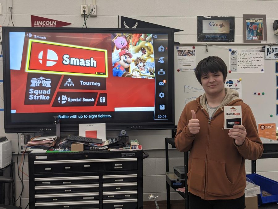 Junior+Gabriel+Tasonis+poses+in+front+of+the+Smash+Bros+level+select+after+winning+the+tournament.+Smash+Bros+Ultimate+is+a+Nintendo+game+that+pits+characters+from+a+variety+of+games+against+each+other+in+brawler-style+battles.