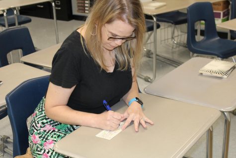 English teacher Whitney Shoemaker fills out a check. She matched her students contributions to this years HOSA fundraiser, helping collect over $3,400.