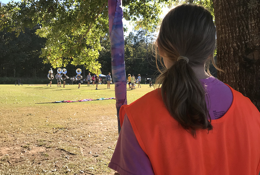 October 6, 2022 - Color guard captain and senior Charlotte Craner watches the marching band review their drills for the show. This years performance is called K-Bach, and involves a lot of integration and visuals provided by the band and color guard. 