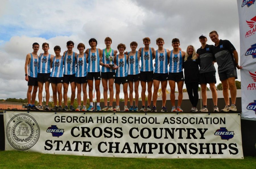 Boys cross country team stands on the podium following their 2nd place finish in the AAAA State Championship. Head coach Kelly Rock praised the team for their camaraderie. The girls team placed 3rd overall. 