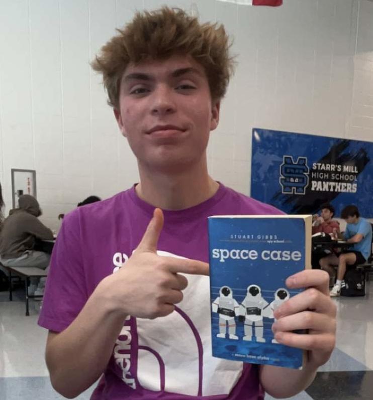 Sophomore Morgan Williams poses with a copy of “Space Case” by Stuart Gibbs. Gibbs has published 39 books and is most famous for his Spy Kids series. 